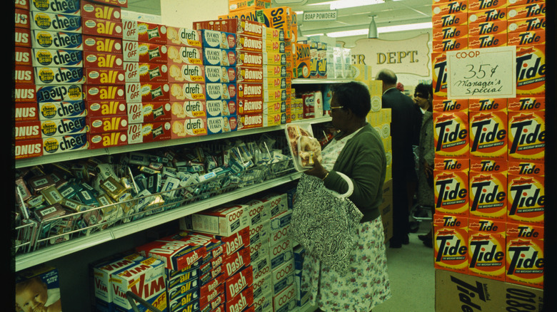 A vintage photo of a woman looking at packages of Dial soap on grocery store shelves