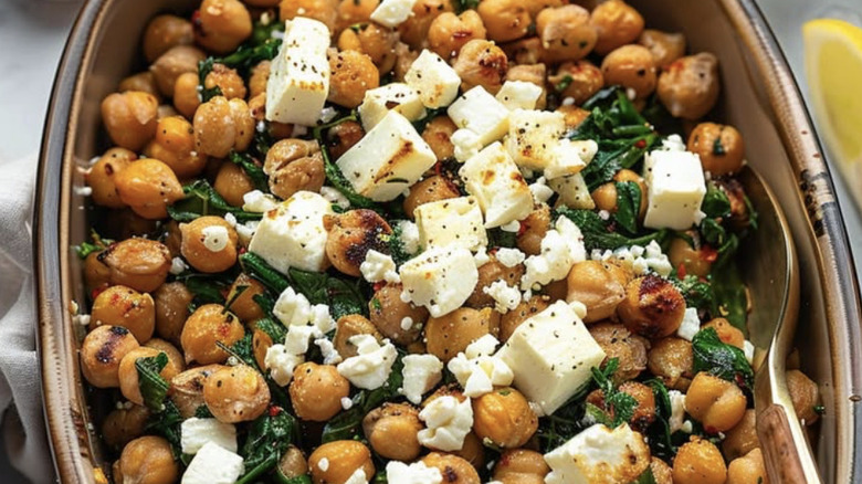 chickpeas, kale, and feta in baking pan with spoon