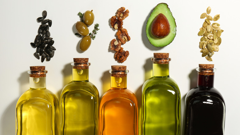 A variety of cooking oils in glass bottles with olives and avocado