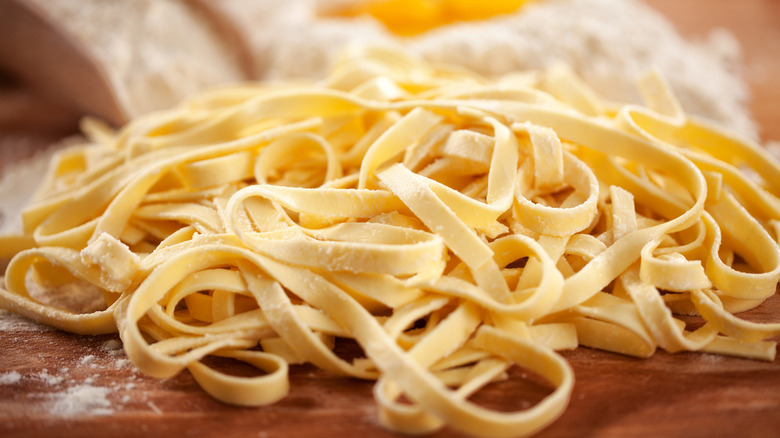 Fresh pasta noodles in a pile on a wooden counter