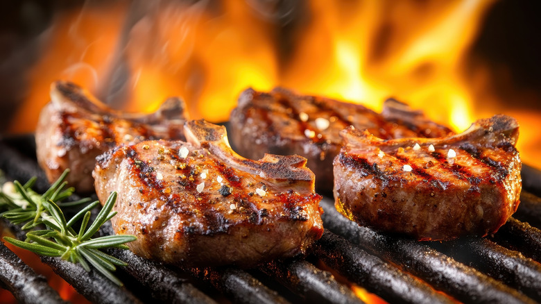 Seared chops on a grill with flames and rosemary