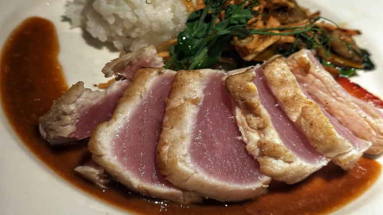 A dry-aged fish from GW Fins, artfully plated with its slices fanned out, served with sauce