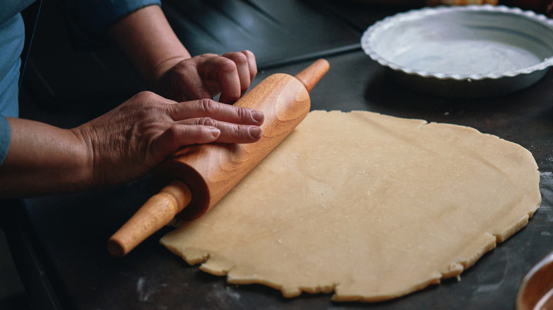 bakers hands rolling out pie dough