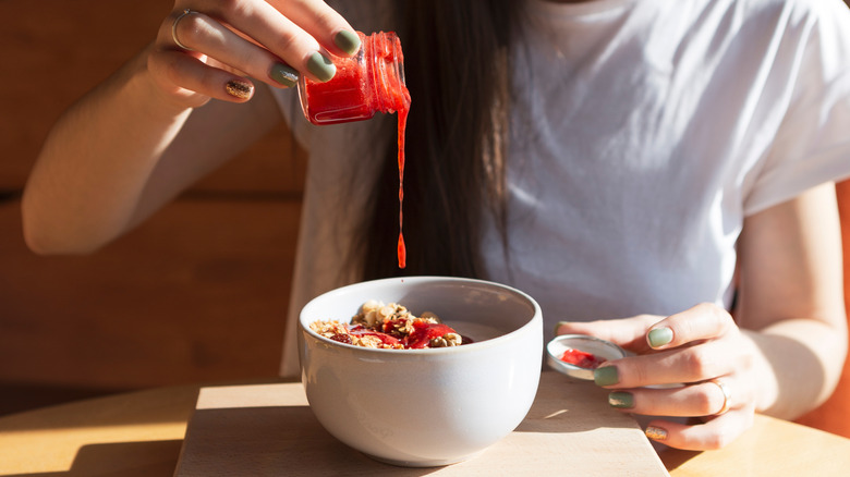 person pouring jam into oatmeal