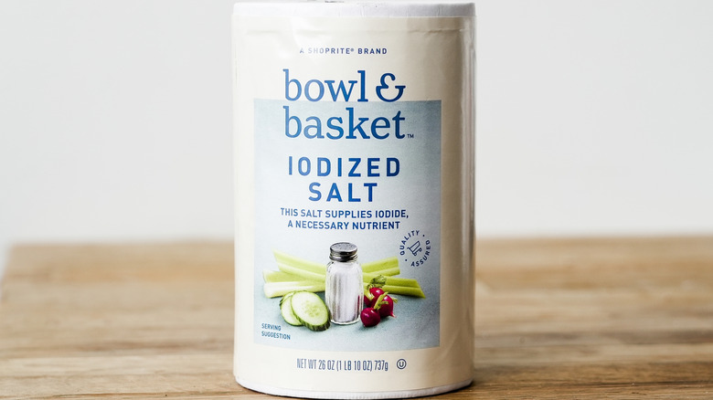 A canister of iodized salt sits on a wooden table