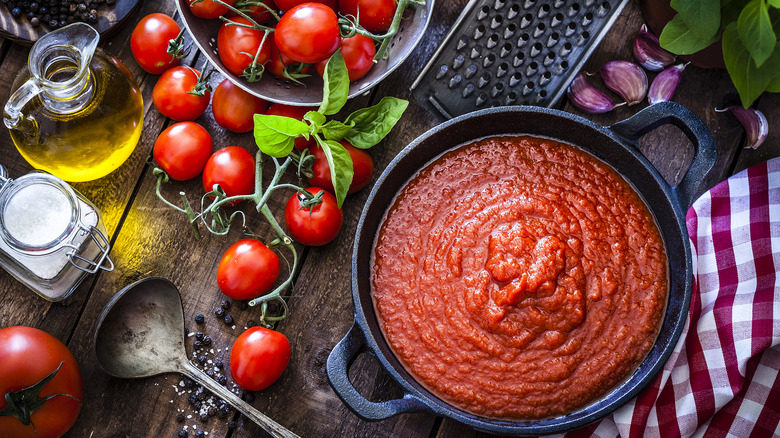 Pot of tomato sauce on a table with other ingredients