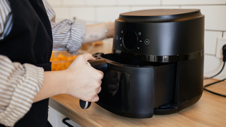 Person pulling the basket from an air fryer