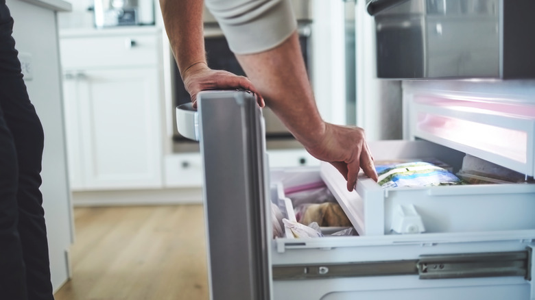 Person reaching into a bottom-drawer freezer