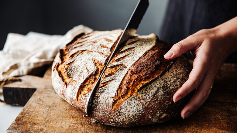 Person slicing  a loaf of bread