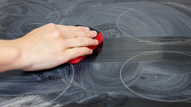 Hand clean induction stovetop with sponge