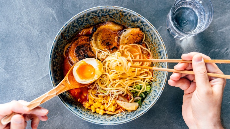 Top-down view of a bowl of ramen with a spoon and chopsticks