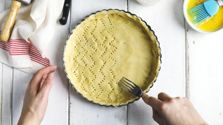 piercing pie crust in a metal tart pan