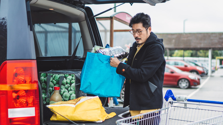 person loading trunk with groceries