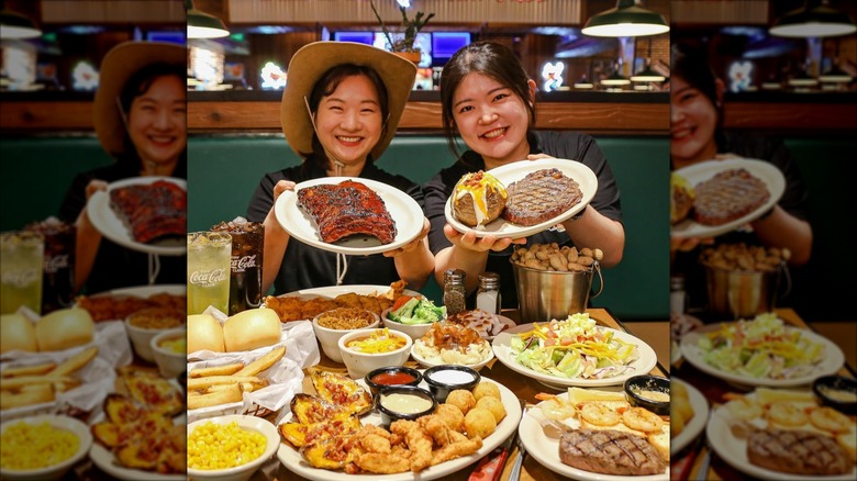 Two people showing off their plates and full table of food at Texas Roadhouse
