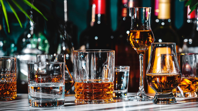 Varieties of whiskey in glasses on a bar table.