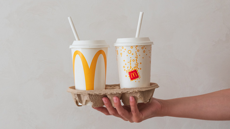 Person holding drink tray with two McDonald's cups