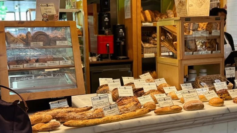 A bakery counter with different types of artisanal bread displayed, complete with labels for each one.