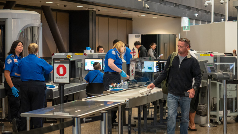 TSA airport security line with passengers and agents