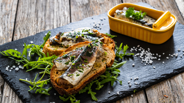 an open can of sardines and some sardines on toast