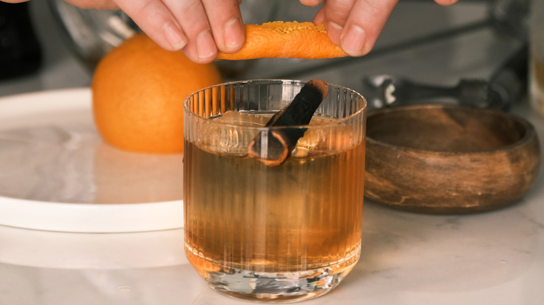 Bourbon cocktail in a glass with orange rind and a cinnamon stick