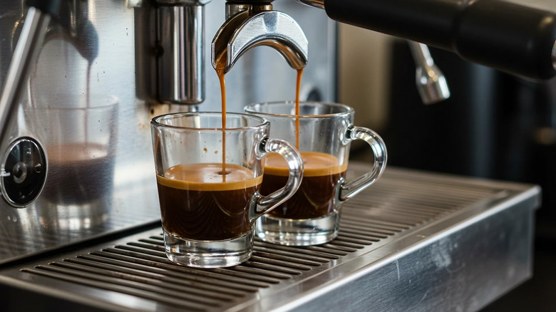 Two glasses being filled with espresso from an espresso maker