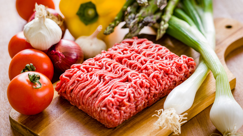 Rectangle of ground beef on a cutting board with vegetables