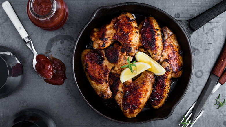 Roasted chicken wings topped with lemon in cast iron pan