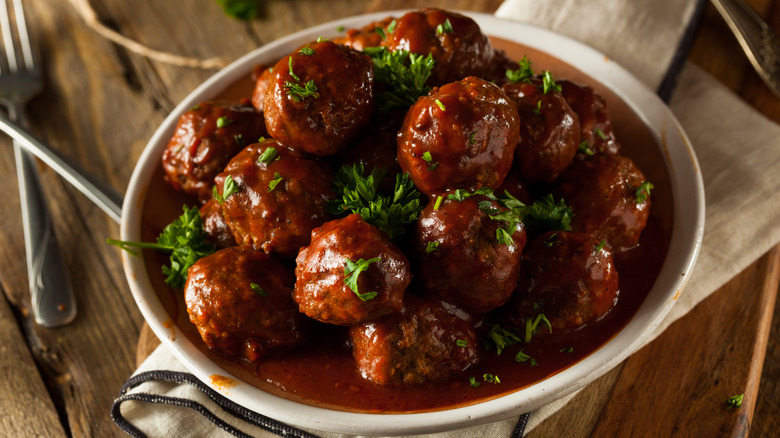 A plate of barbecue meatballs is dressed with herbs