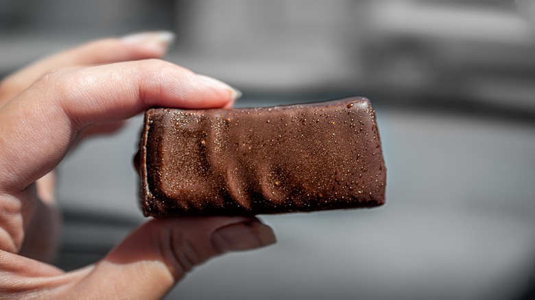 A hand holding a frozen homemade, chocolate-covered candy bar.