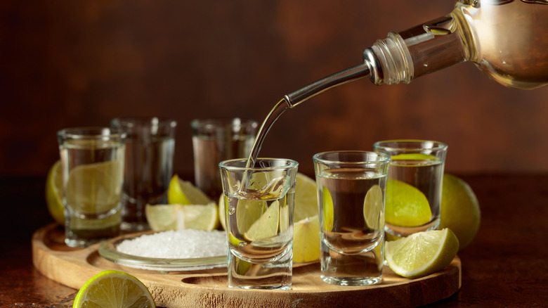 Pouring tequila shots on a tray with salt and lime slices