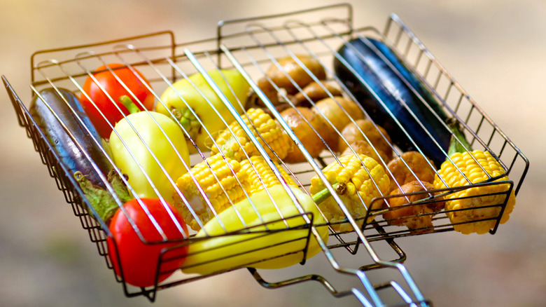 A mix of vegetables in a clamped down grill basket, ready to go on the grill.