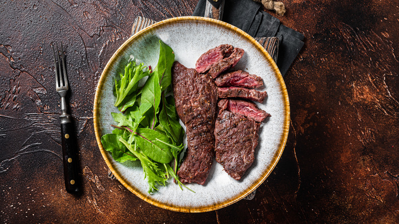 Steak and greens in a plate with a fork on the side