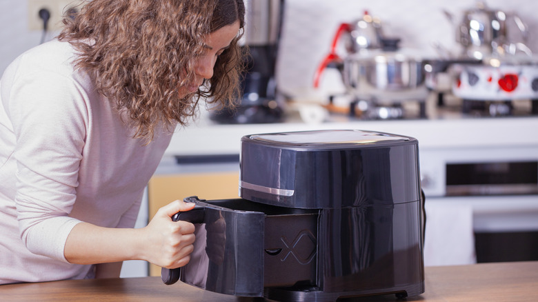 Woman opening air fryer drawer