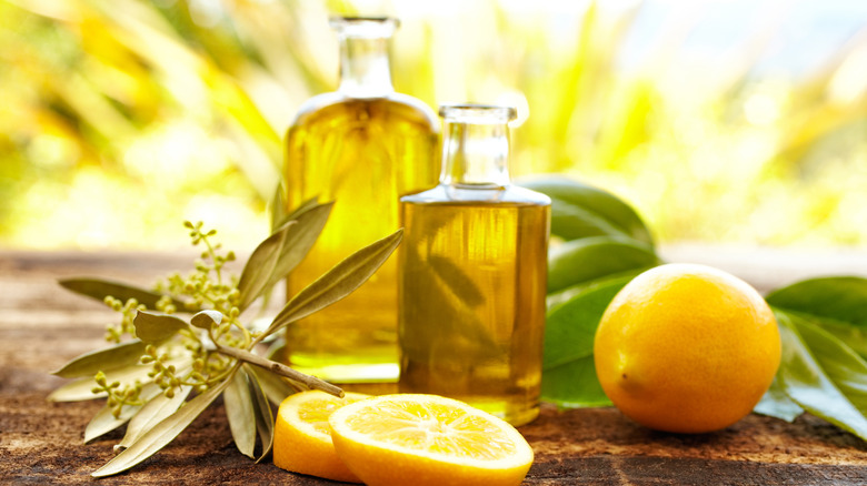 Bottles of oil with lemons on table.