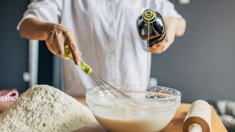 Man pouring olive oil into batter