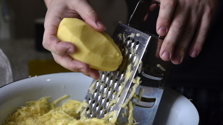 Shredding potatoes on a box grater.