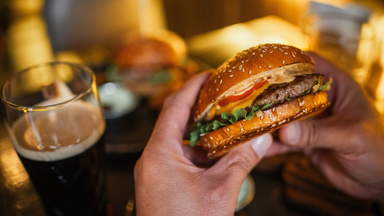 Close-up of a person's hands holding a cheeseburger