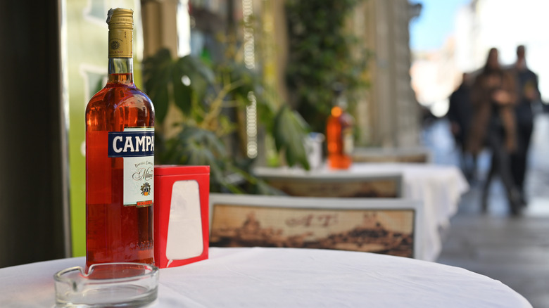 A bottle of Campari on a sidewalk cafe table.