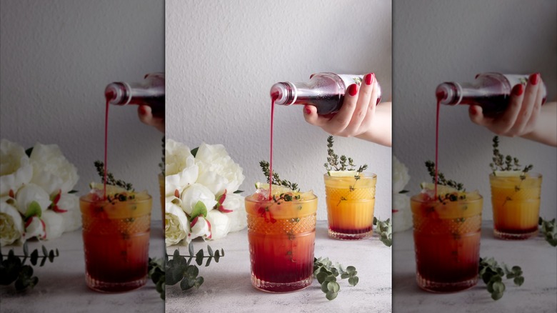 Person pouring grenadine into a glass
