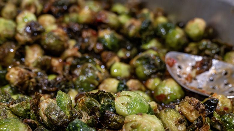 Pan filled with roasted Brussels sprouts and a serving spoon