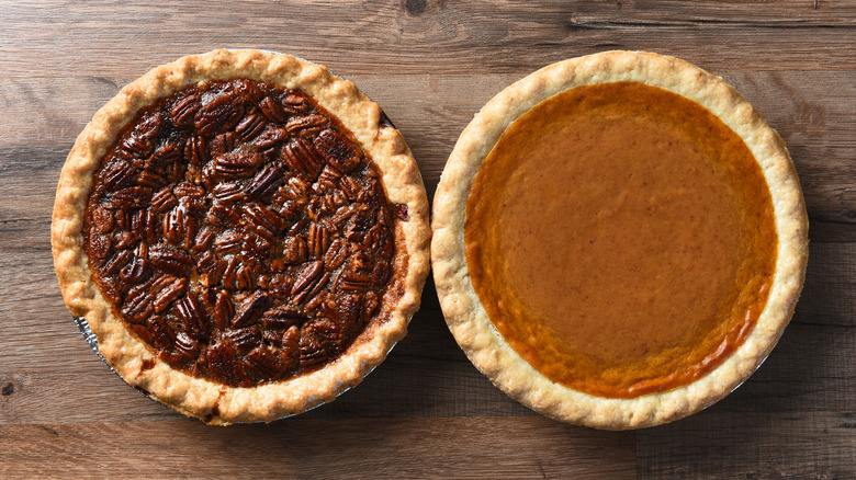Pumpkin and pecan pies, seen from above, sitting on wood table