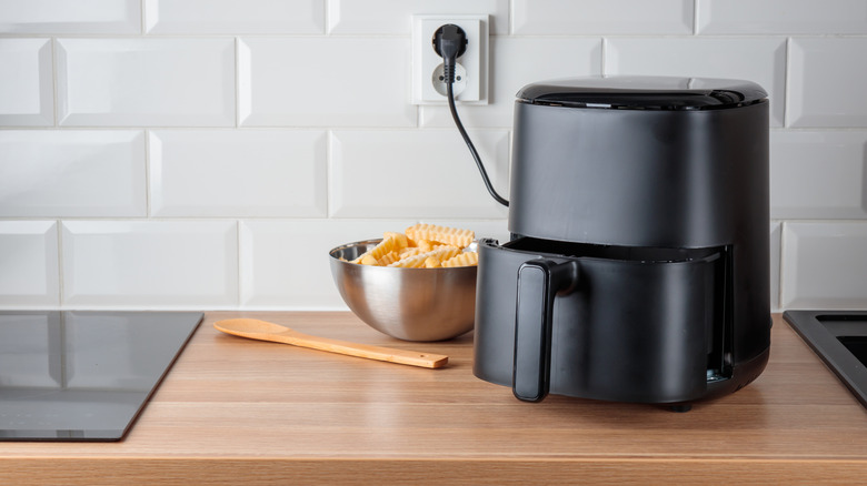 black air fryer sitting on a wooden kitchen counter