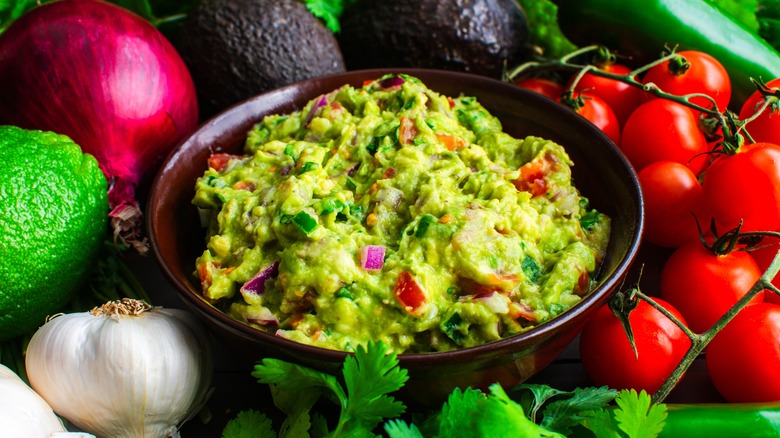 Bowl of guacamole surrounded by its ingredients