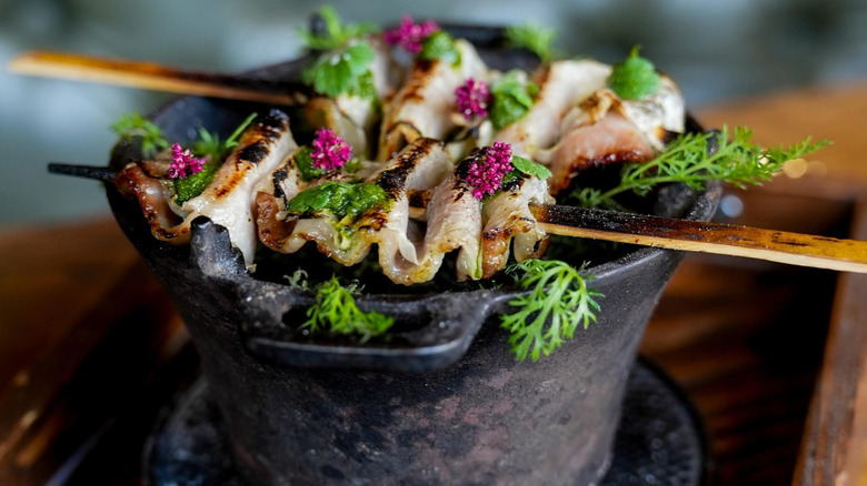 Skewers of fish resting on a stone bowl