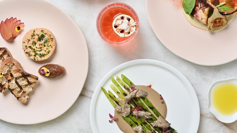 White plates of artfully arranged vegetable dishes and a passion fruit cocktail photographed from above
