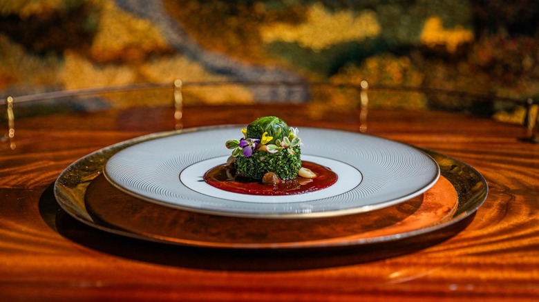 A fine-dining plate presentation decorated with greens and edible flowers