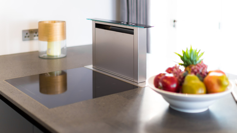 High-tech downdraft stainless stove beside bowl of fruit