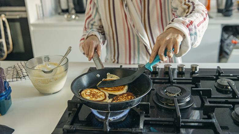 Person cooking pancakes on a gas stove