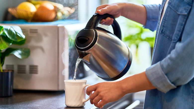 pouring hot water from kettle into mug