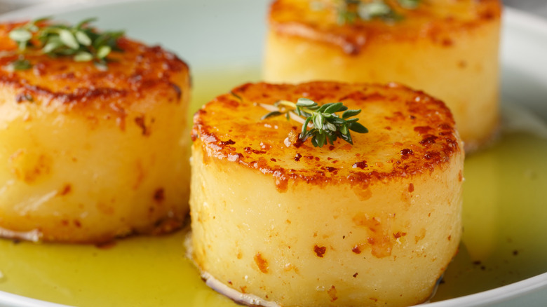 A closeup of scalloped potatoes topped with thyme.